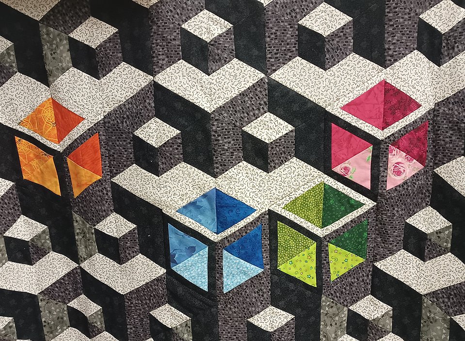 Bild på textil gjord i lappteknik, med kuber som mönster.