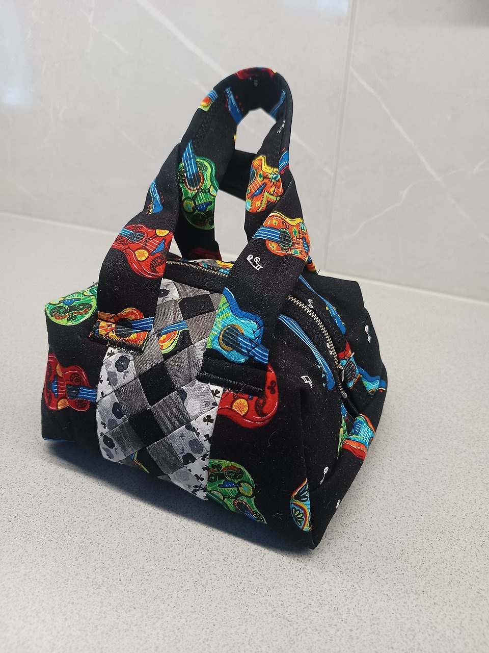 Bild av handväska i textil, gjord i lappteknik. 
