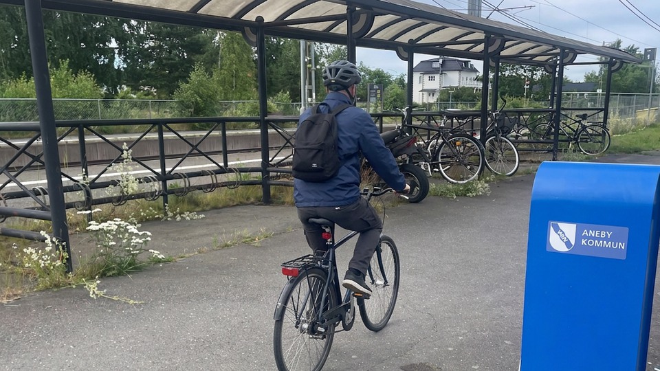 En man som cyklar längst med ett cykelställ vid stationen.