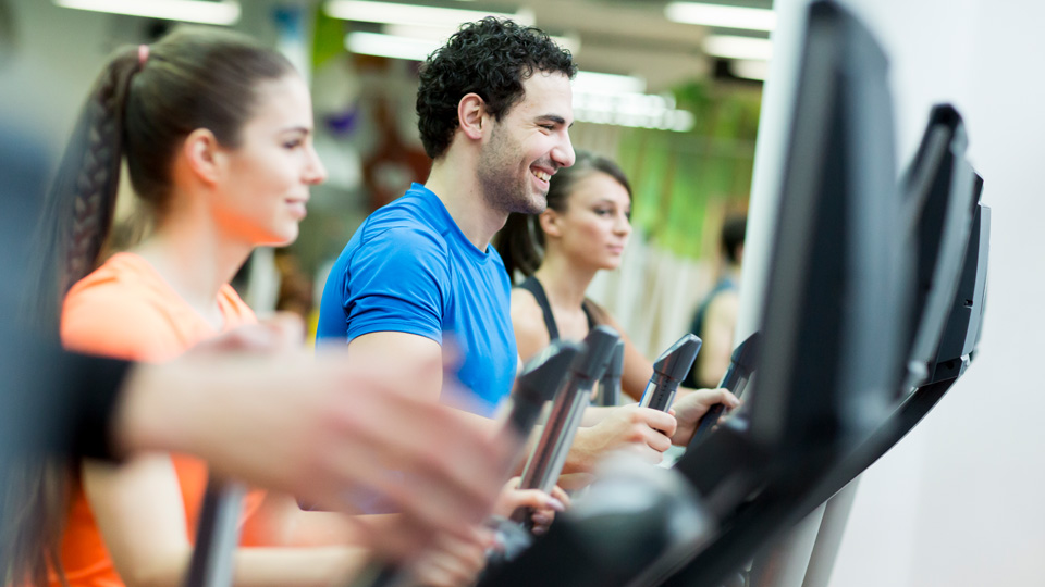 Tre unga vuxna på var sitt löpband på gymmet. 