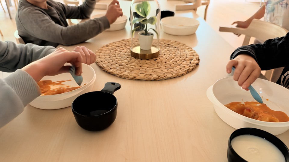 En grupp barn som sitter runt ett bord och äter.