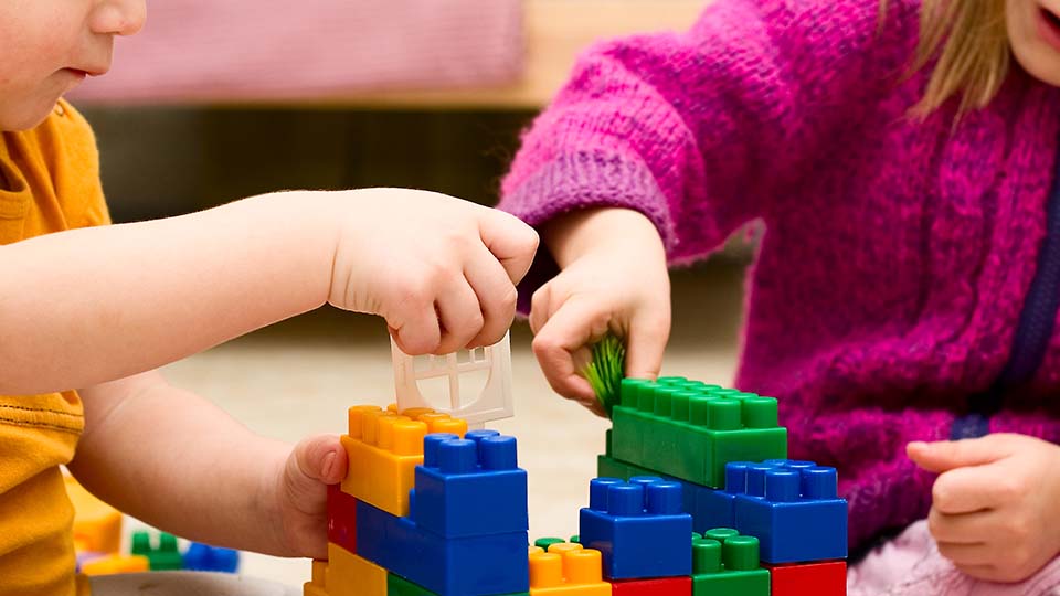 Närbild på barn som leker och bygger med lego.