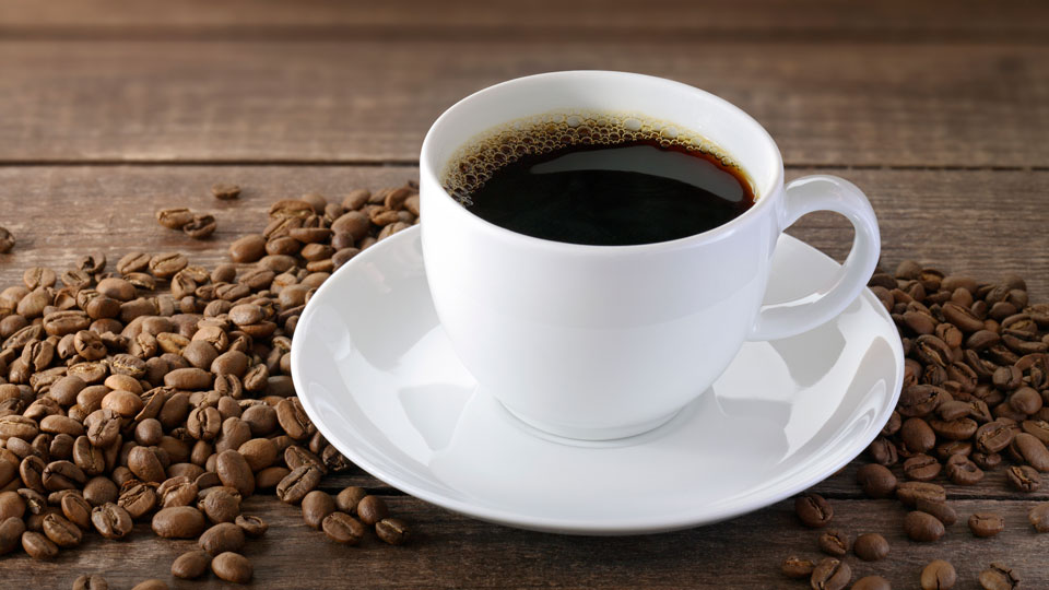 Kaffekopp fylld med kaffe på ett fat. Foto,