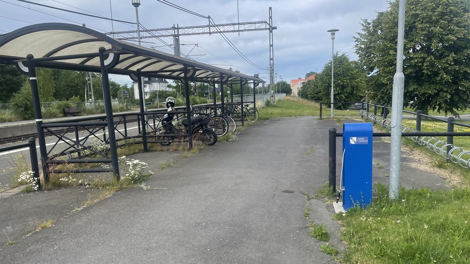 Cykelställ jämte en järnväg, med en blå cykelpump bredvid.