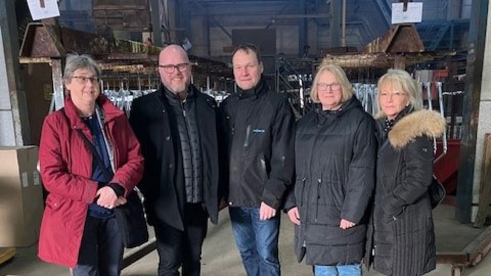 Personer står uppradade i en företagslokal. 