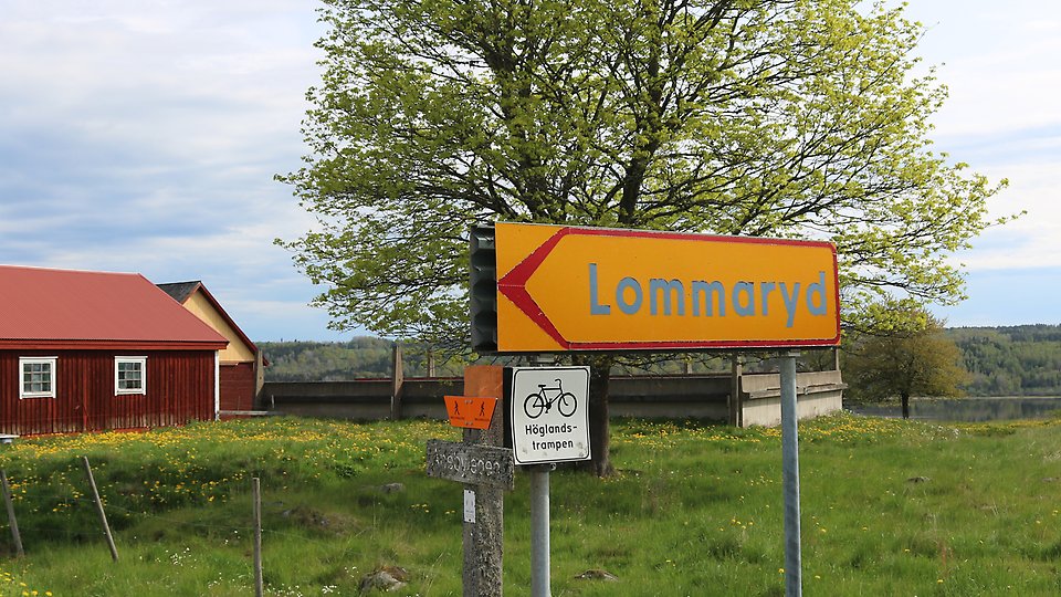 Vägskyltar där det står Lommaryd och Höglandstrampen på. Bakgrund öppet och grönt landskap. Foto