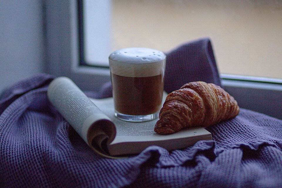 Foto. Kaffekopp placerad på öppen bok.
