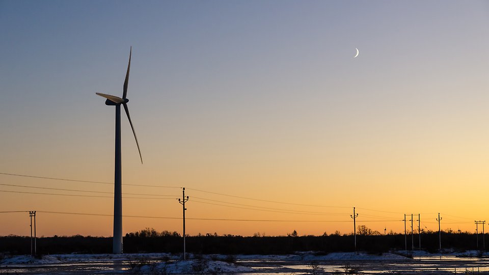 Bild på ett vindkraftverk vid en solnedgång. Foto